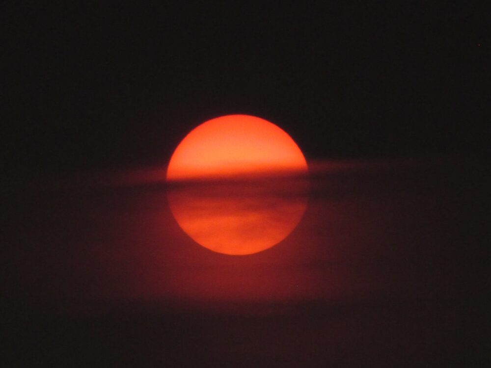 Sun behind clouds. Photo by Mourya (https://unsplash.com/photos/EwawqhV2Doc)
