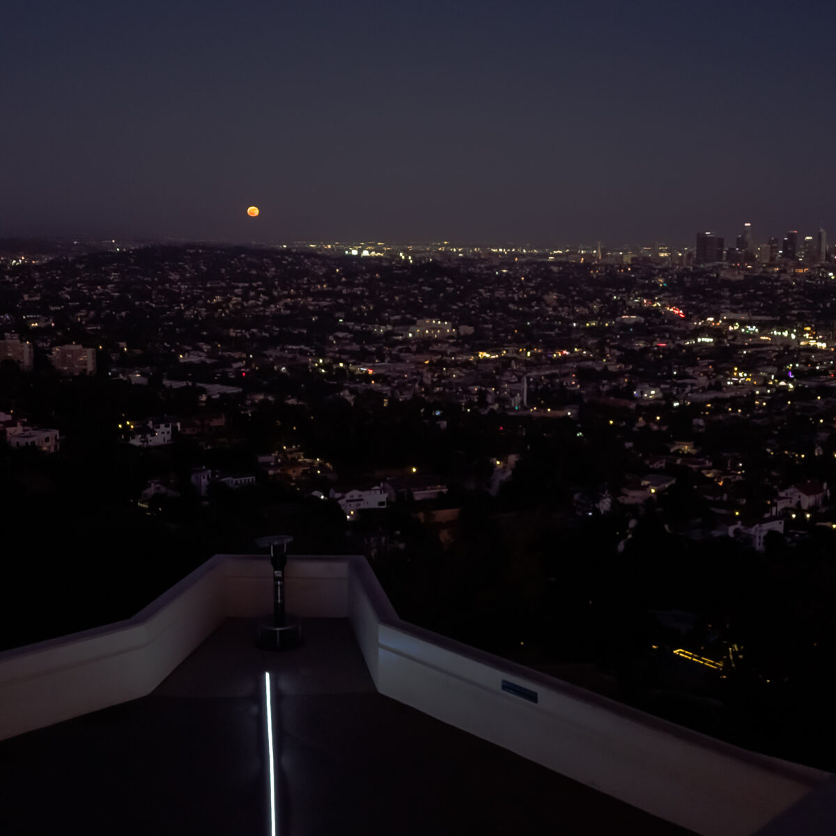 An orange moon rising on the eastern horizon