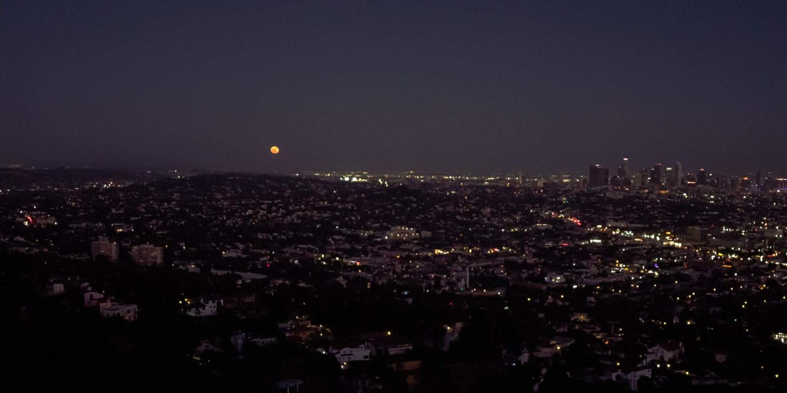 An orange moon rising on the eastern horizon