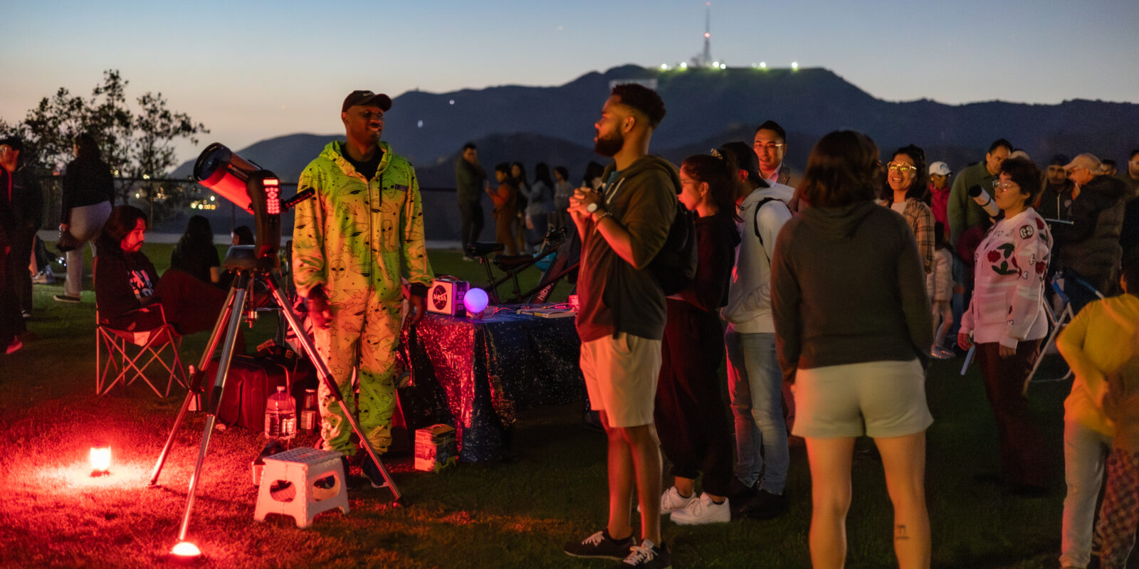 A Telescope Demonstrator greets a line of people waiting to look through the lawn telescope.