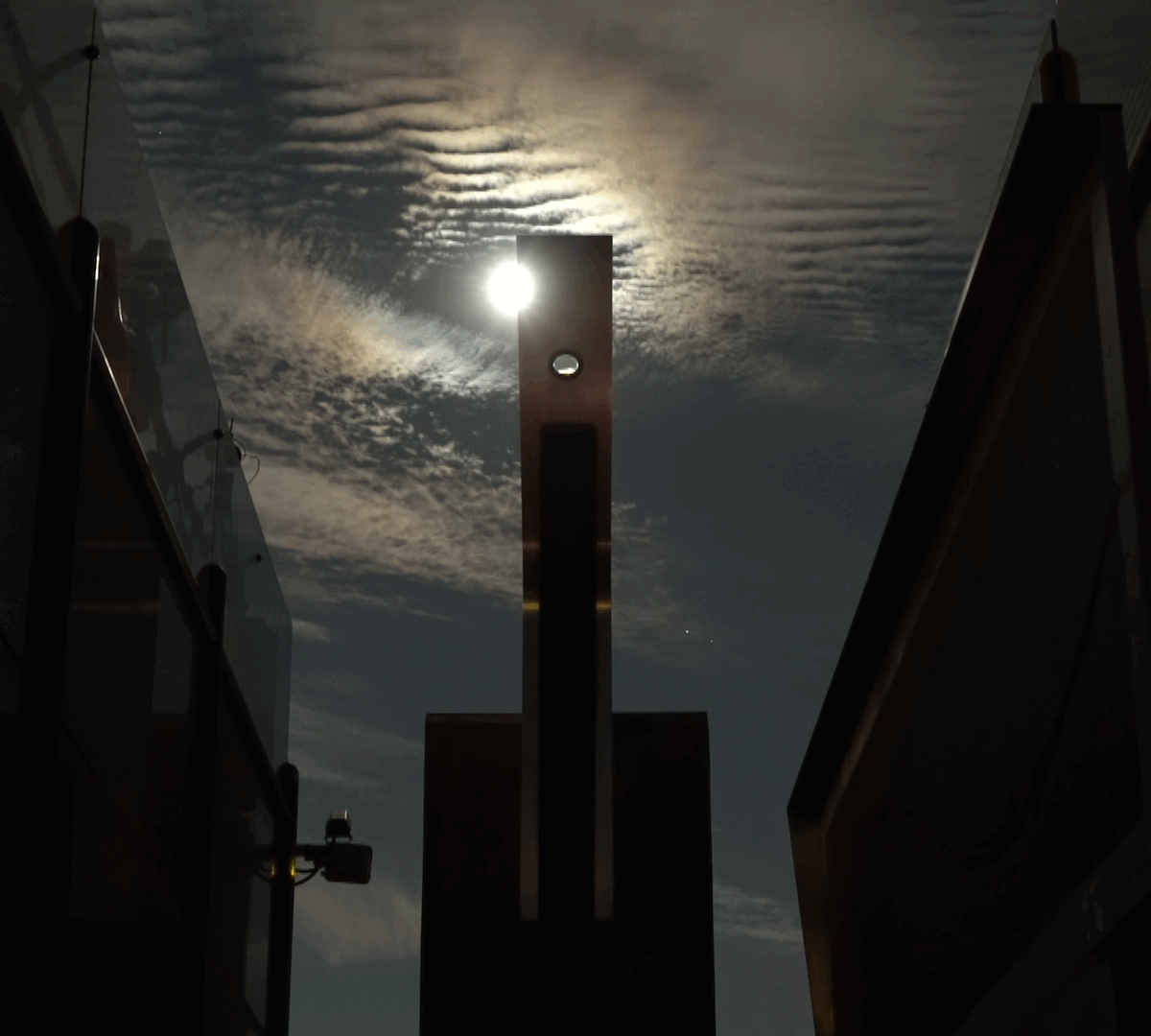 The moon crossing over the aluminum monolith.