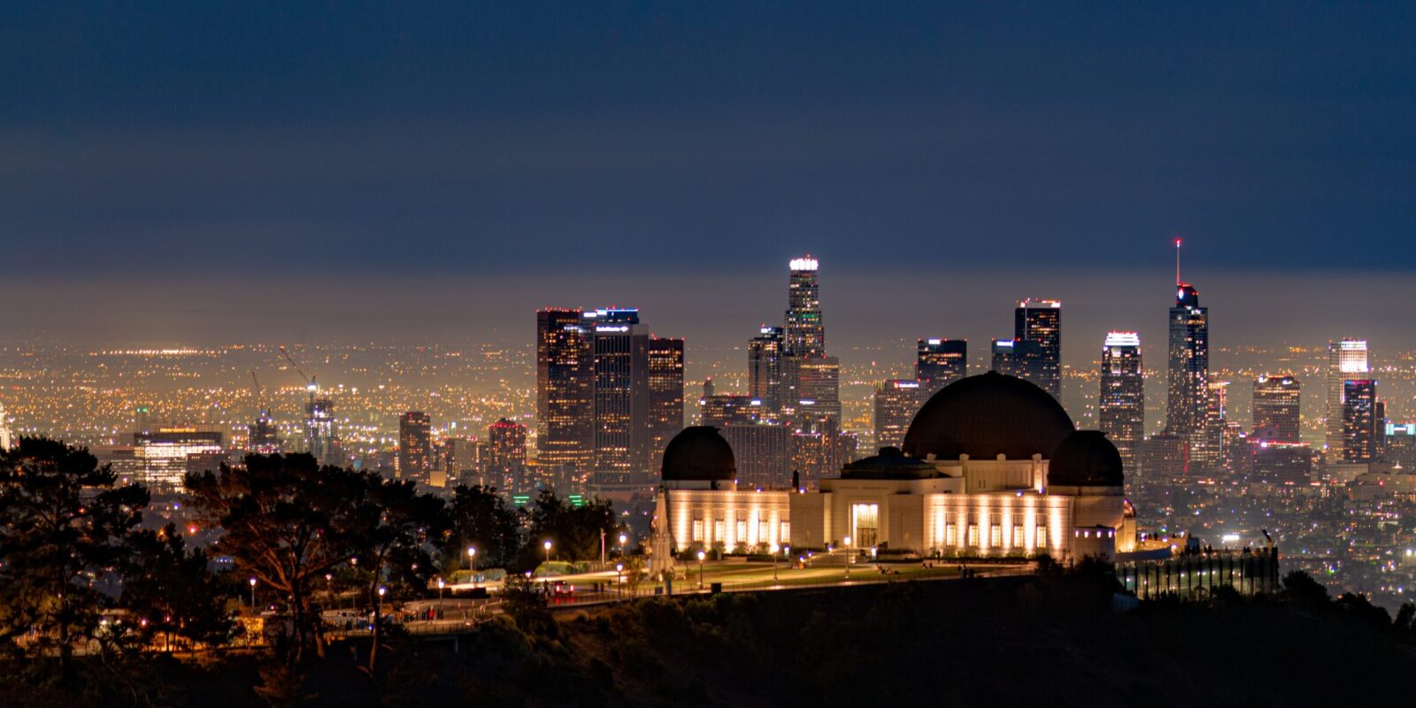Griffith Observatory and Downtown Los Angeles glitter from a mountain trail on a clear night.